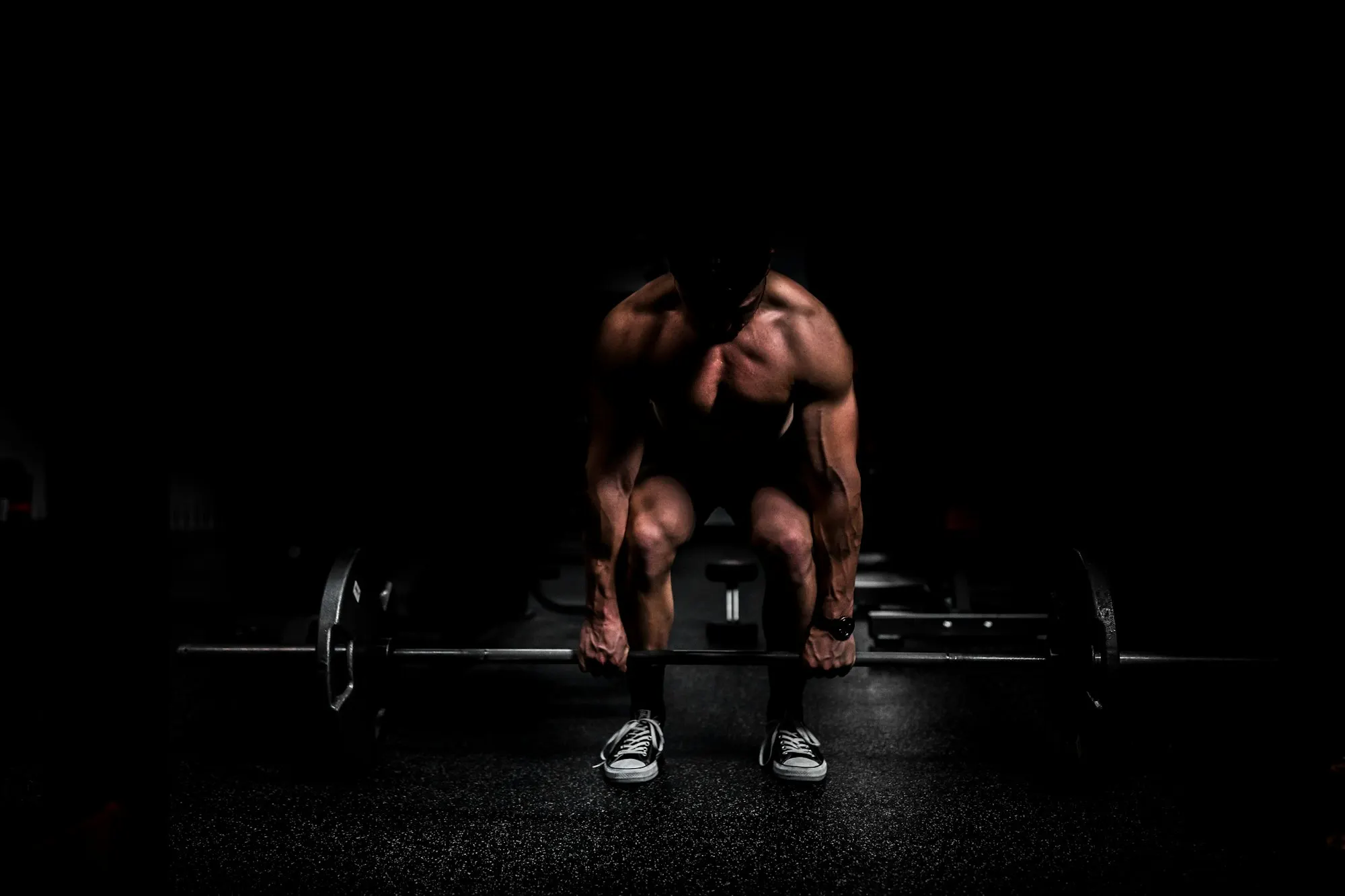 Athlete setting up a heavy deadlift in a dark gym